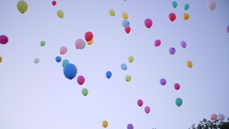 Multicolored party ballons flying in the sky sunset time.