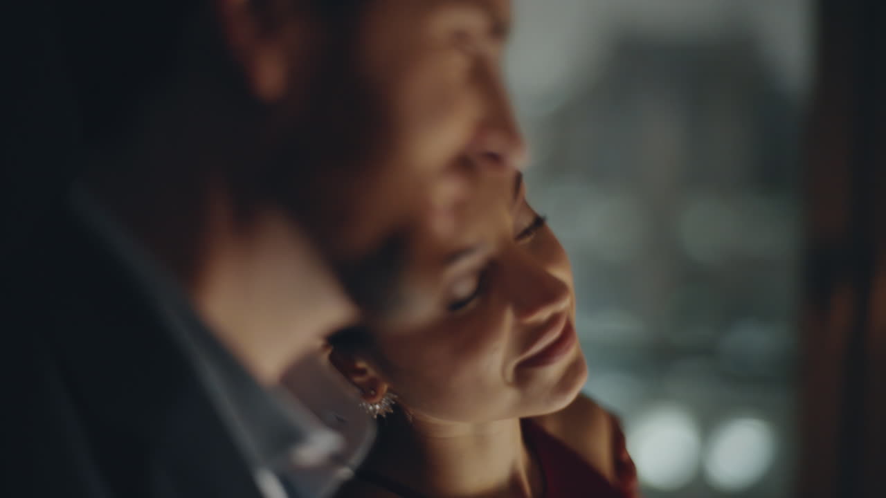 저녁의 연인들은 어두운 창문 방에서 서로를 가까이서 바라보고 있다. 남편이 아내를 포옹하고 있다.