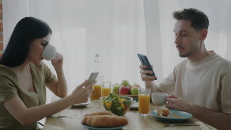 couple having breakfast and using their phones