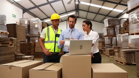 gerentes de almacén y trabajadores mirando la computadora portátil