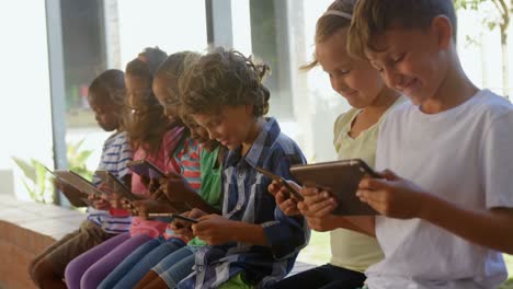 Side-view-of-mixed-race-schoolkids-using-digital-tablet-in-the-corridor-4k