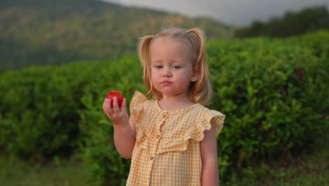 little girl eating an apple in a tea plantation