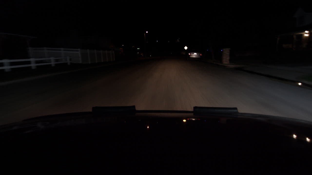 A hood of a car point of view driving at night a dark road headlight show the world