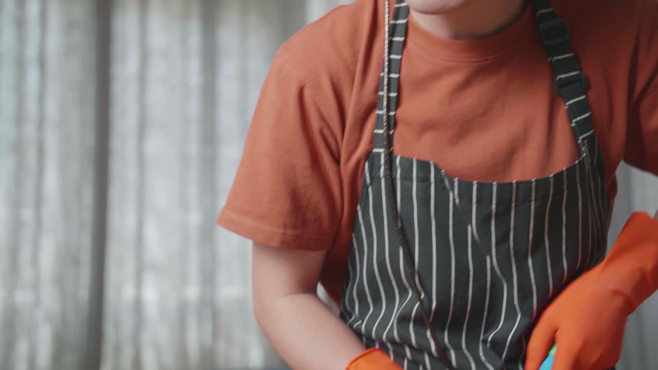 primer plano de una ama de casa asiática con un delantal disfrutando de limpiar el suelo en casa