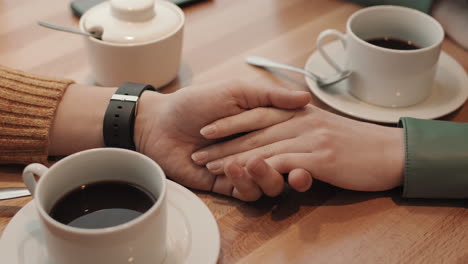 un hombre y una mujer enamorados tomados de la mano en un café.