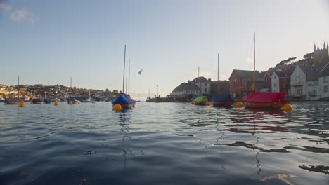 Möwe-Fliegt-über-Festgemachte-Segelboote,-Die-Im-Fluss-Fowey,-Cornwall,-Low-Angle-Wide-Schwimmen