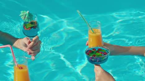 friends toasting drinks in a pool