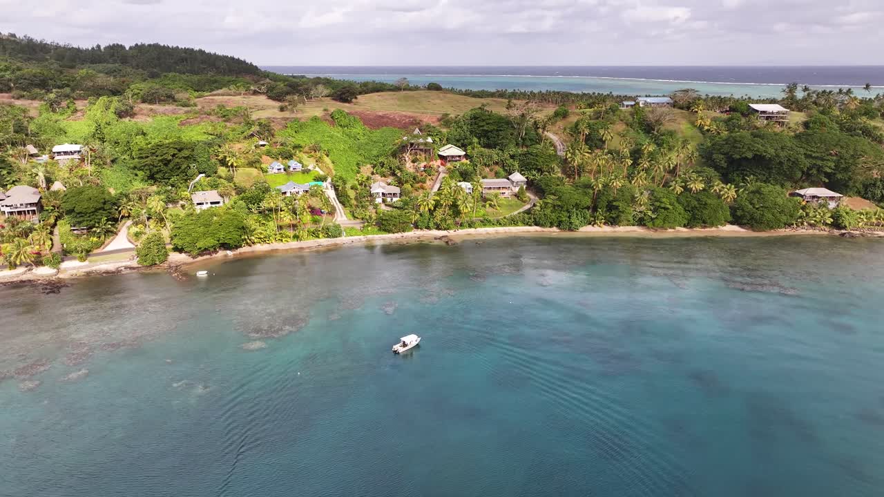Pristine tropical shoreline of Vanua Levu island in Fiji. Houses and small hotel buildings. Drone