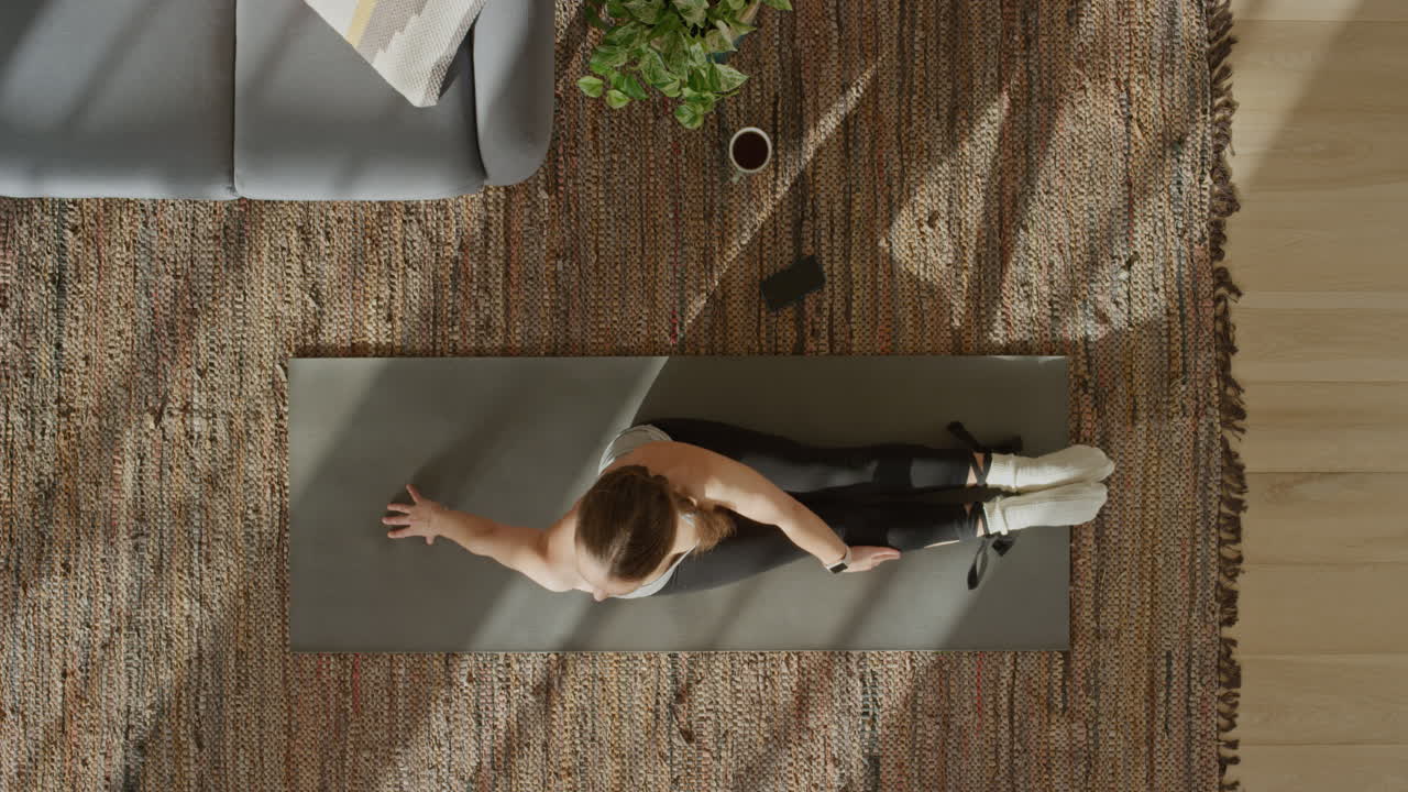 vista superior mujer de yoga ejercitando un estilo de vida saludable estirando el cuerpo flexible disfrutando del entrenamiento en casa practicando atención plena en la colchoneta de ejercicios