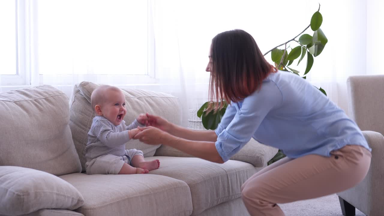 소파 에 작은 아기 와 함께 행복 한 어머니 춤
