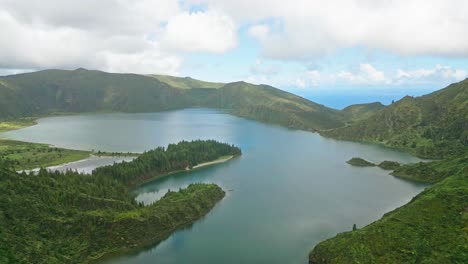 Serene-aerial-view-of-Lagoa-do-Fogo-lake-surrounded-by-lush-green-hills-and-mountains