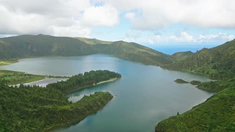 vista aérea serena del lago de lagoa do fogo rodeado de exuberantes colinas y montañas verdes