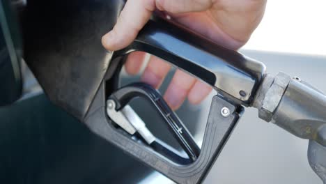 gas station pump handle being inserted then depressed and removed from green car gas tank at gas or petrol station.