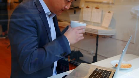 businessman using laptop while having cup of coffee