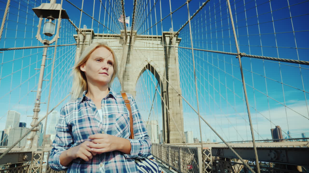 뉴욕 미국 여행에서 브루클린 다리를 따라 여유롭게 걷는 여성 관광객