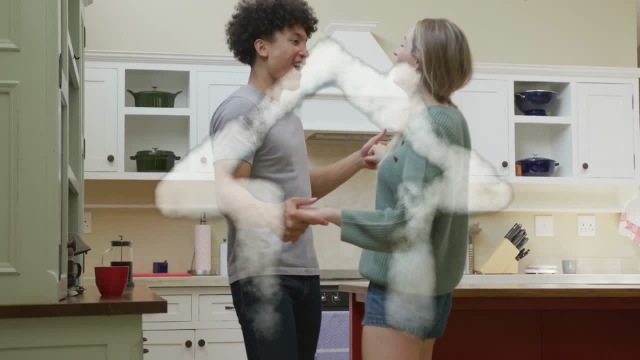 Animation of cloud house over happy diverse couple dancing together in kitchen