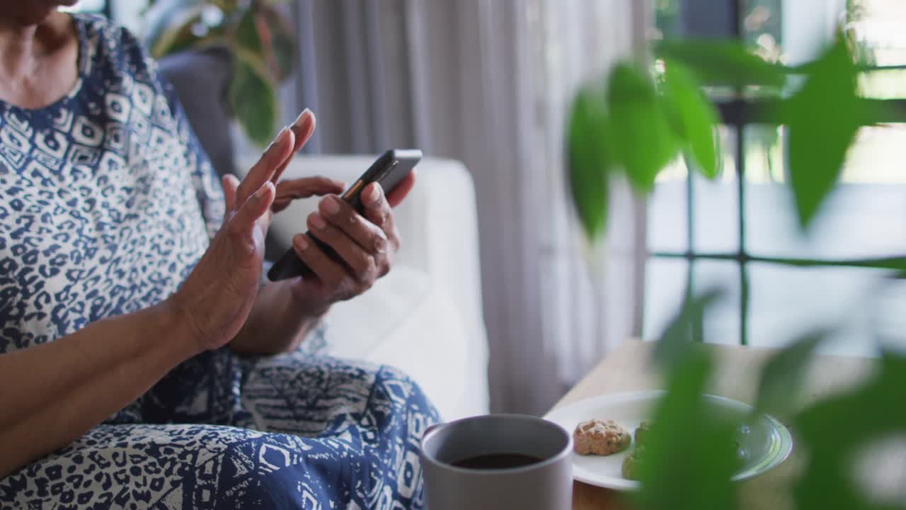 소파에 앉아 스마트폰을 사용하는 아프리카계 미국인 여성