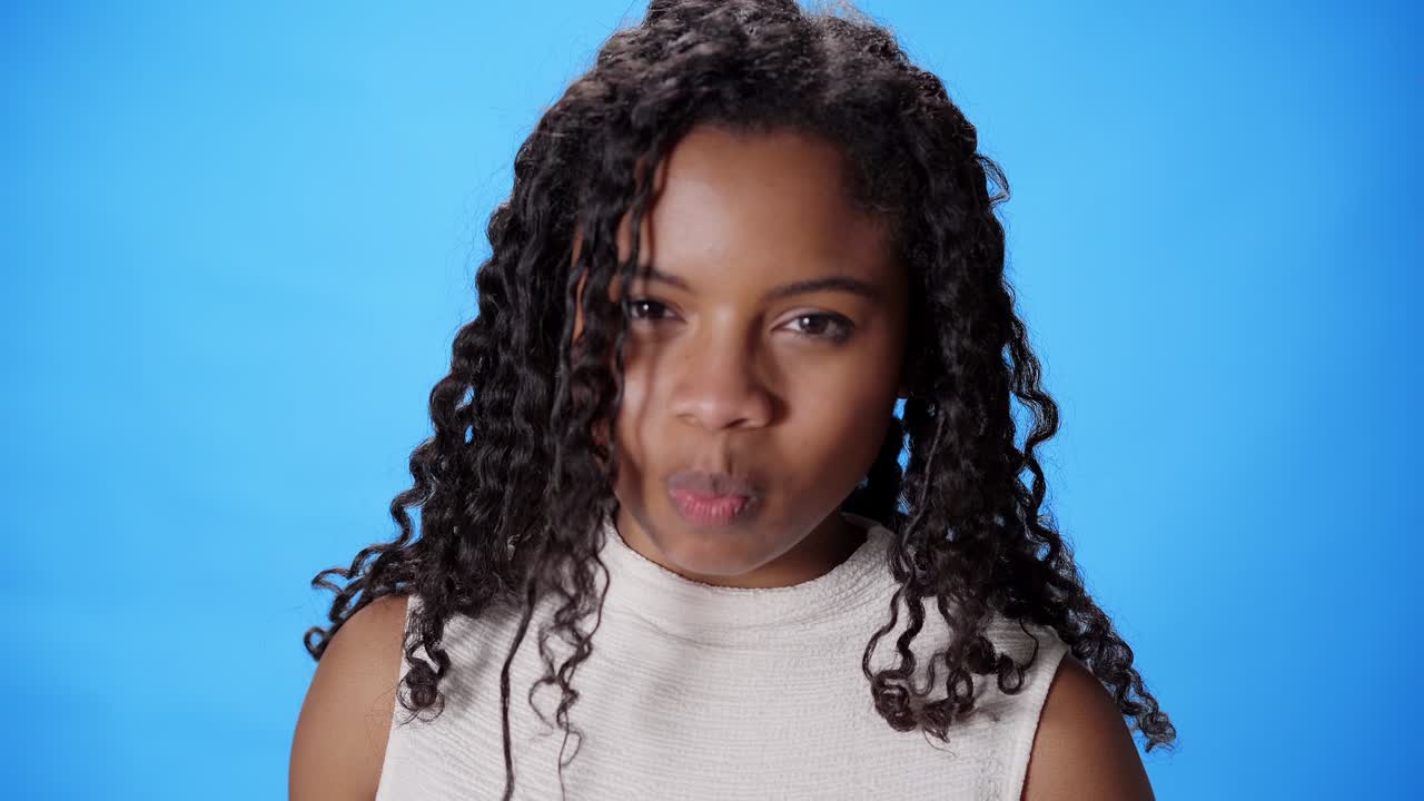 un primer plano de una joven sonriente comiendo fruta en un cuenco sobre un fondo azul.