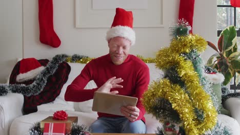 happy albino african american man wearing santa hat making video call at christmas