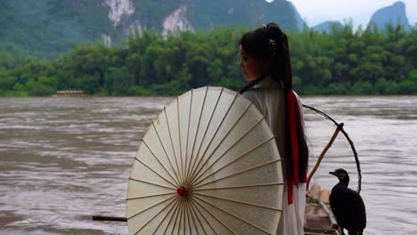 ragazza della dinastia han con i capelli lunghi e un ombrello accanto a un cormorano sul fiume li