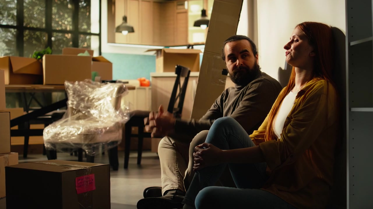 Tired Couple Resting on Floor After Moving Into New Home