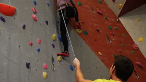 Coach-assisting-a-woman-in-climbing-the-artificial-wall-4k