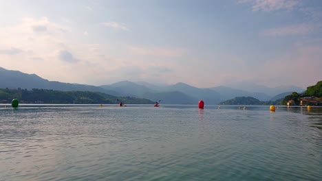 two athletes on canoes between buoys paddle towards center of orta lake