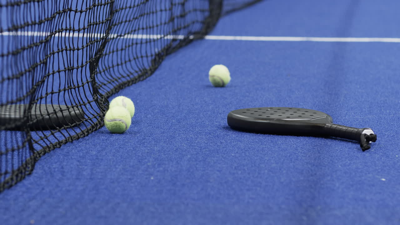 Padel racket and tennis balls on indoor court, ready for exciting match, copy space