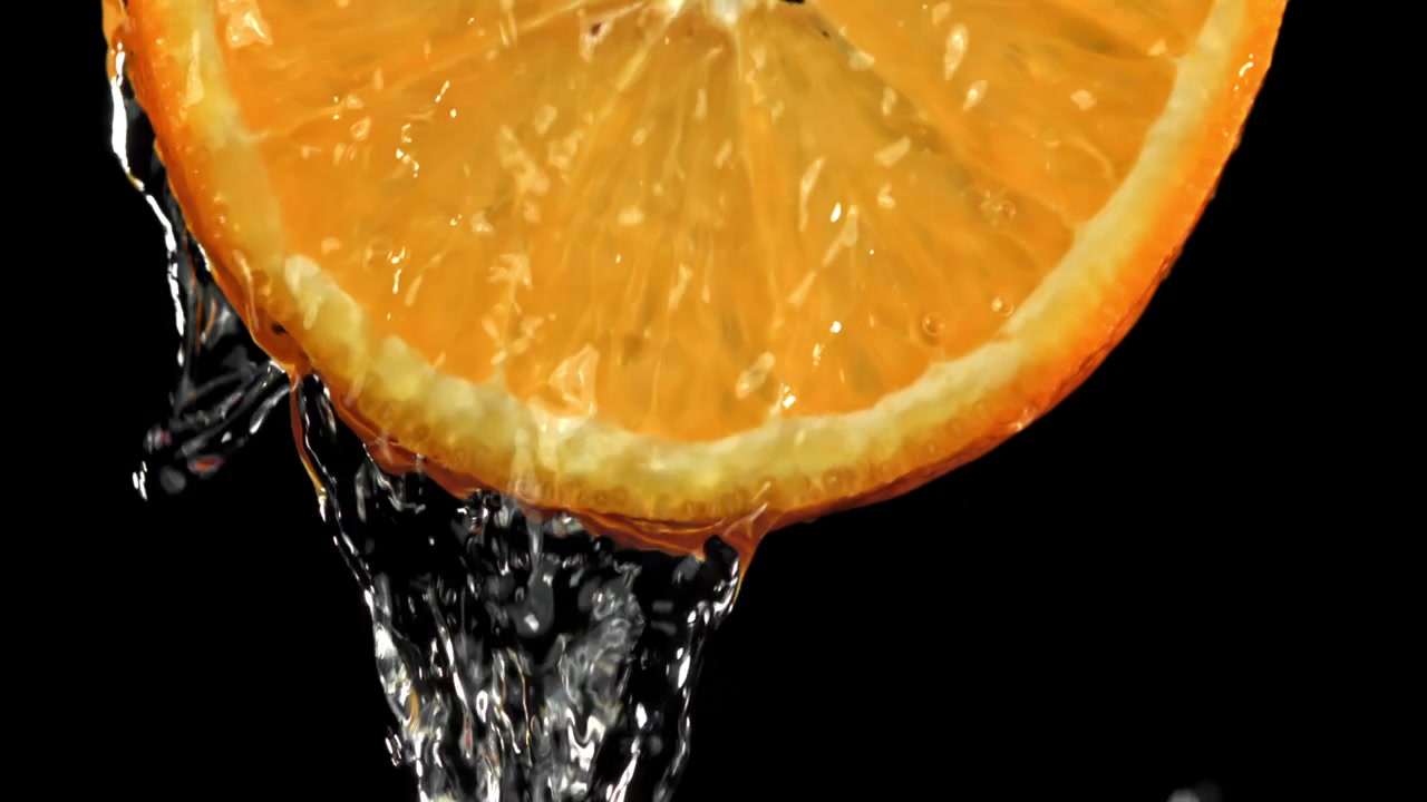 Acqua rinfrescante schizza su una fetta d'arancia succosa.