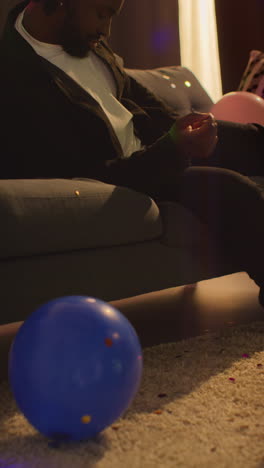 video vertical de un hombre tendido en el sofá después de beber alcohol en una fiesta de casa sufriendo de resaca