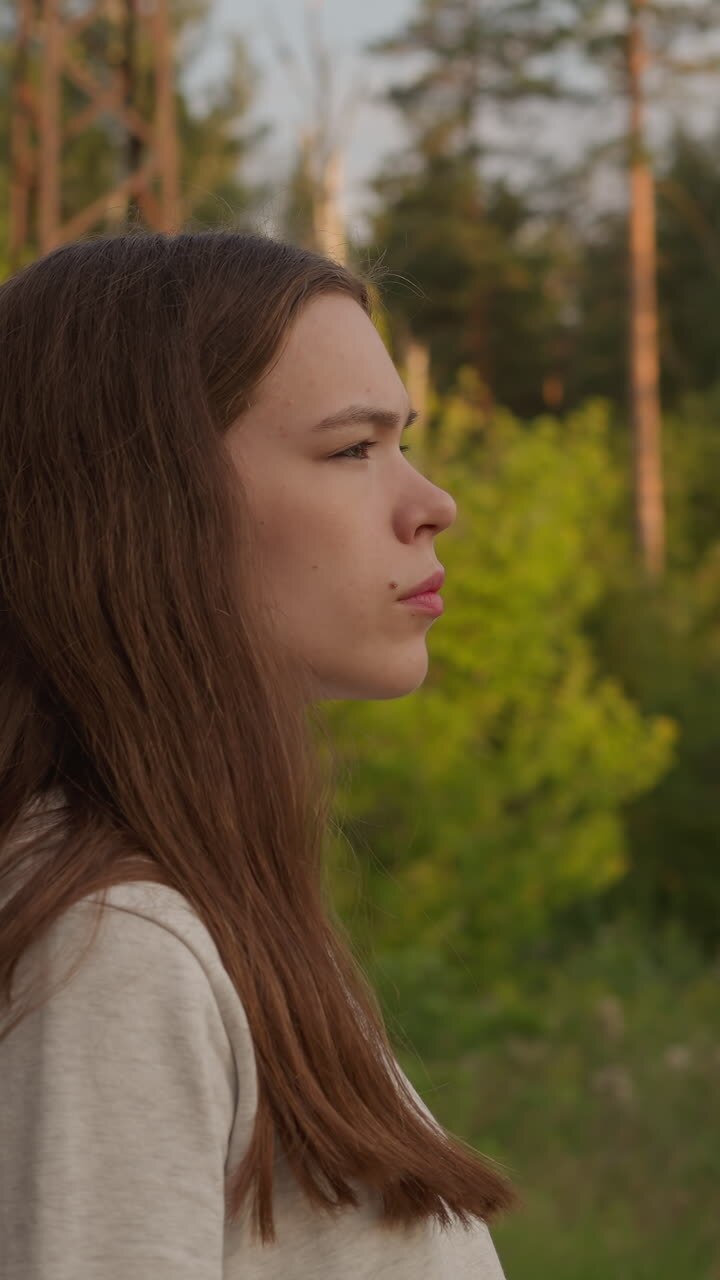 Woman stands near forest in evening. Young lady looks frustrated thinking about what to do next. Walking alone in fresh air to find mind harmony