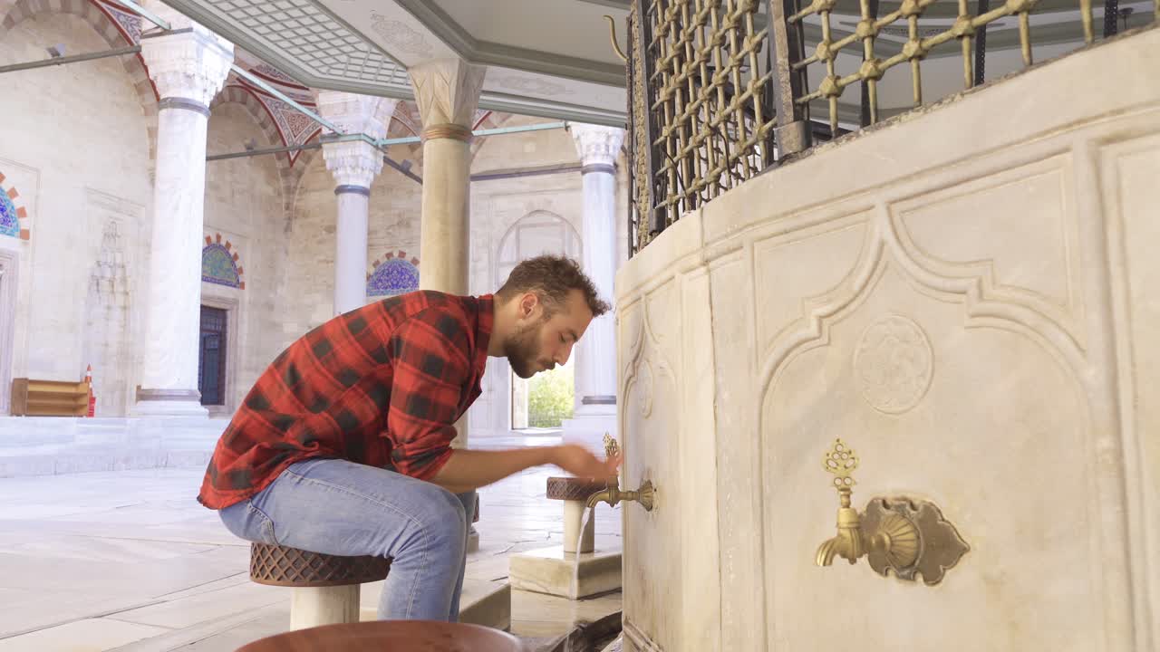 Muslim young man performs ablution in the fountain.