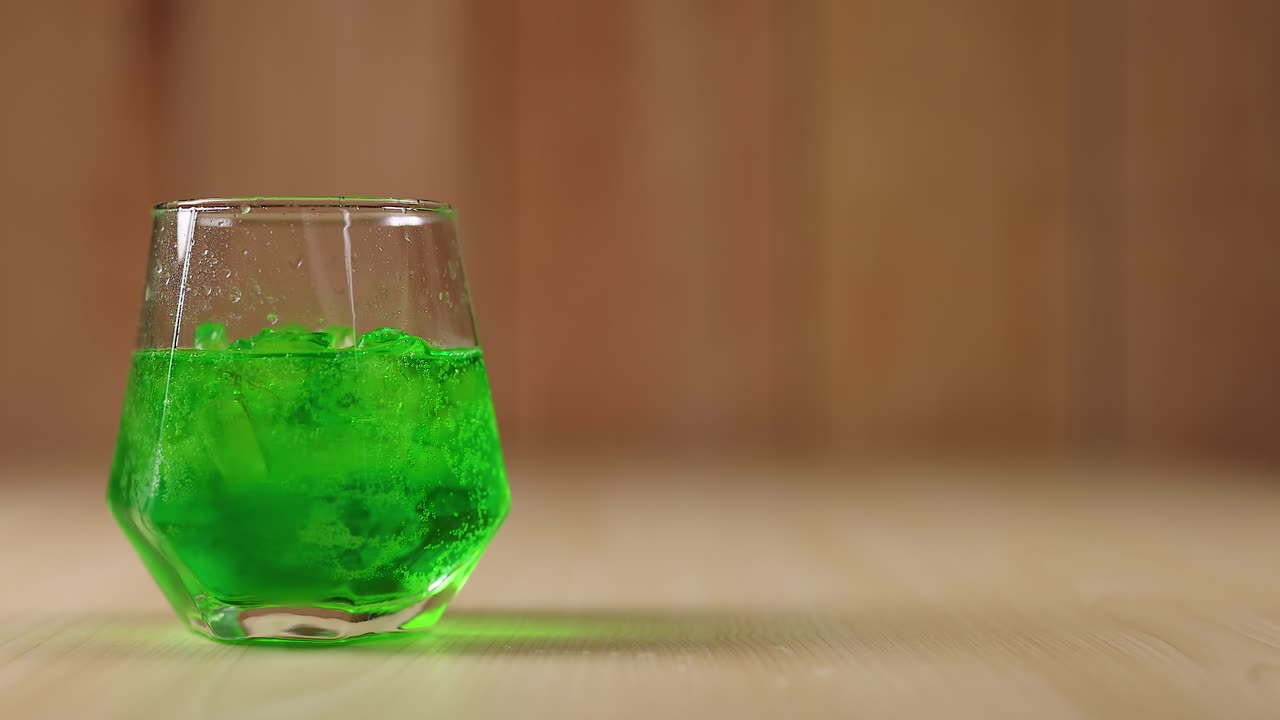 líquido verde en vaso con cubos de hielo