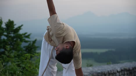 hombre estirando y haciendo yoga postura en la cima de la colina al amanecer al amanecer