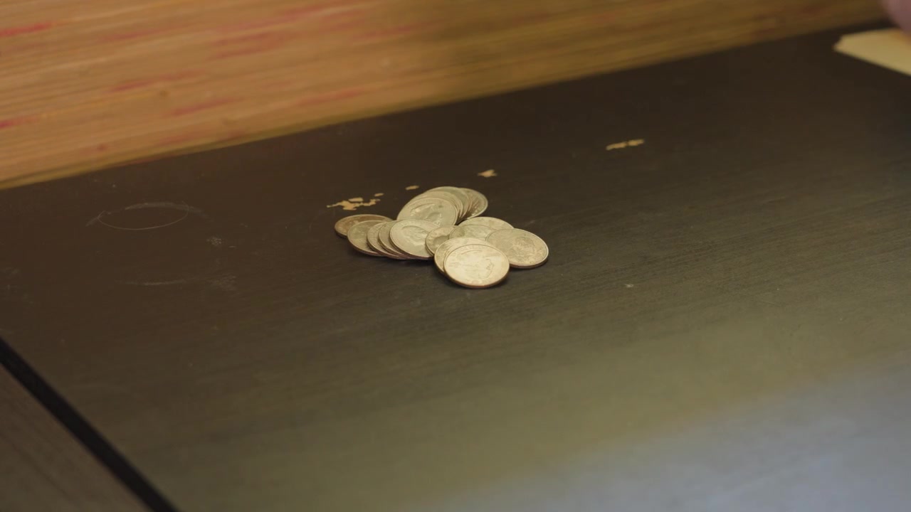 Placing a stack of USD Quarters onto a table.