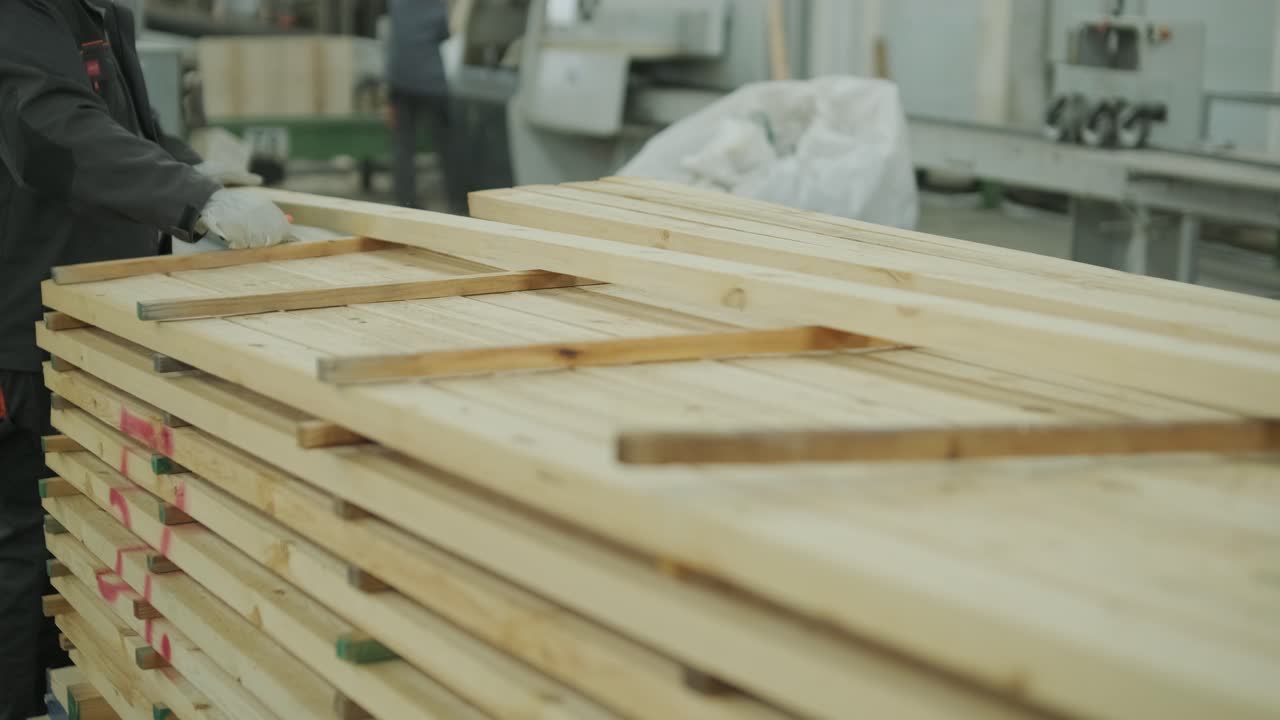 Operaio che impila tavole di legno in una fabbrica di lavorazione del legname