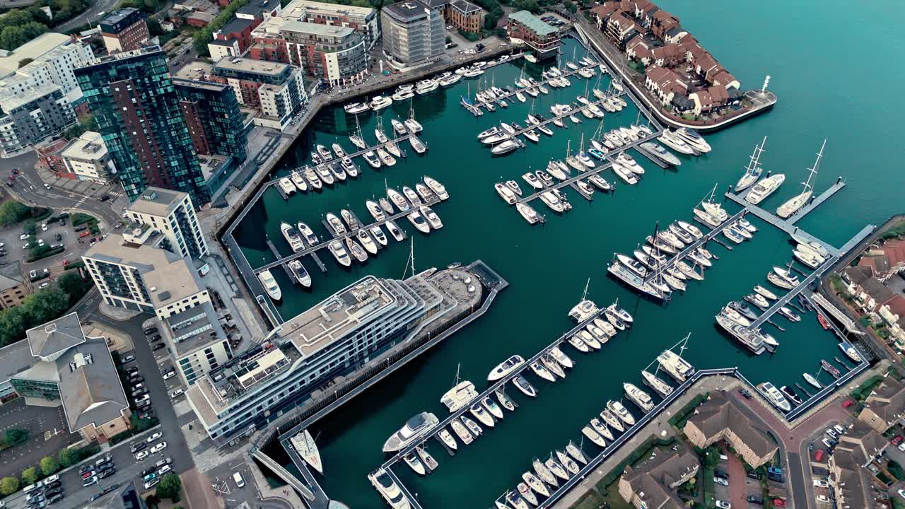 Aerial drone footage of Ocean Village marina in Southampton, showcasing boats, docks, buildings, and waterfront real estate under soft daylight at sunset shot during autumn