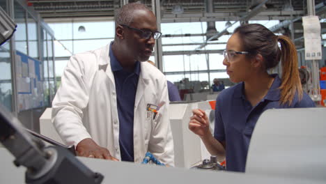 engineer teaching apprentice how to use machine in factory
