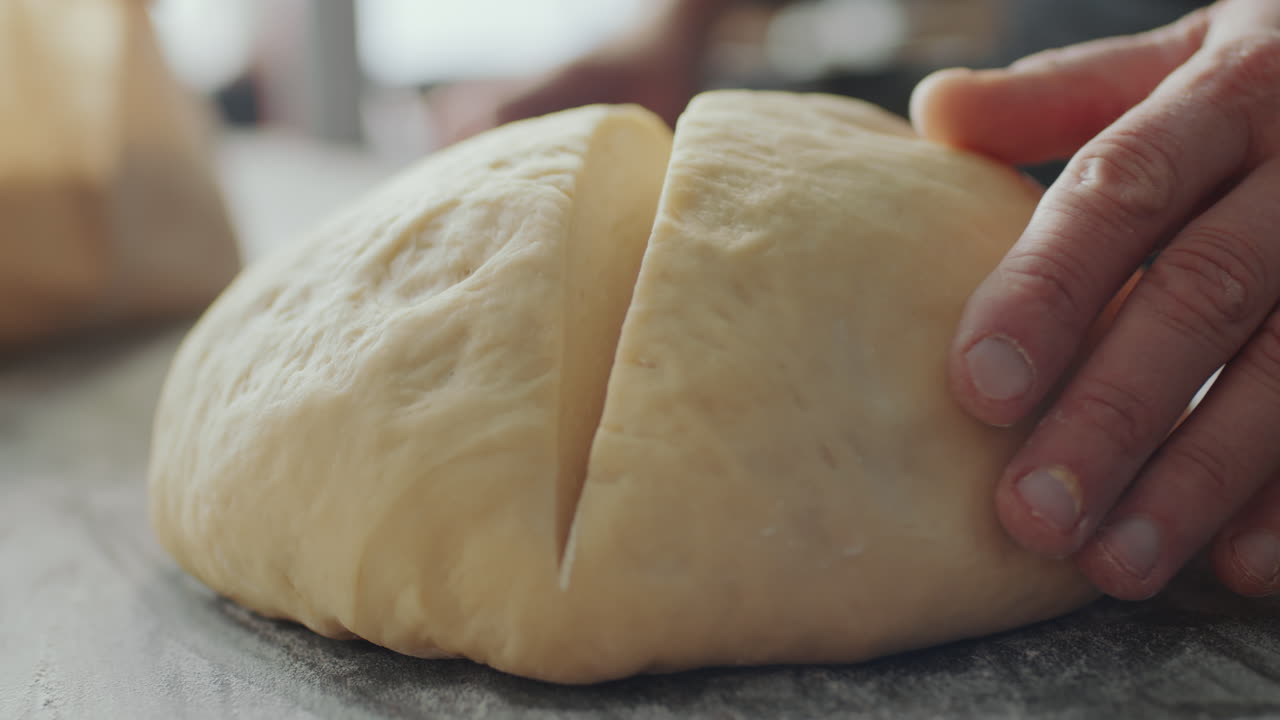 베이커 의 손 이 칼 으로 반죽 을 잘라내는 것