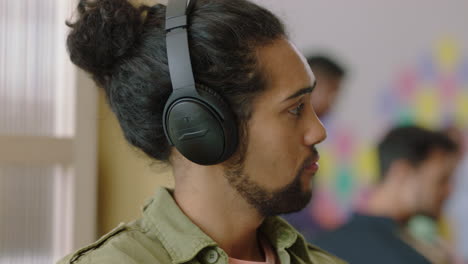 retrato en primer plano joven de raza mixta hombre estudiante relajante escuchando música con auriculares disfrutando de una oficina moderna ocupada