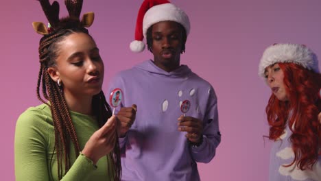 studio shot of gen z friends dancing at christmas party wearing santa hat and reindeer antlers