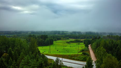 Lapso-De-Tiempo-De-Nubes-Grises-De-Tormenta-Moviéndose-Sobre-Campos-Verdes-Y-Bosques