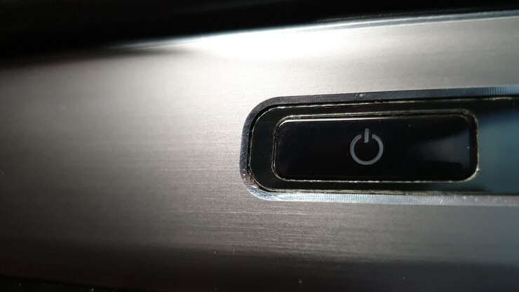 Pulsante di accensione del laptop con luce LCD pulsante che indica la modalità sospensione, su superficie in alluminio spazzolato con accumulo di sporco e sudiciume