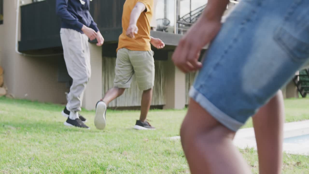 다양한 행복한 남성 십대 친구들이 정원에서 축구를 하고, 느린 움직임