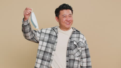 Asian man taking off medical mask flu treatment cure ending of pandemic quarantine disease recover