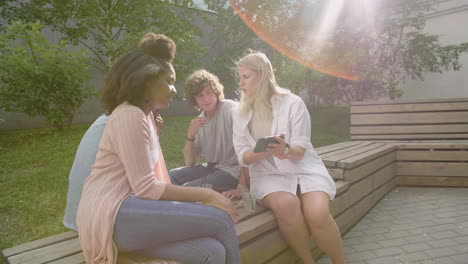joven rubia mostrando algo interesante en el teléfono móvil a sus amigos multiétnicos en un parque 1