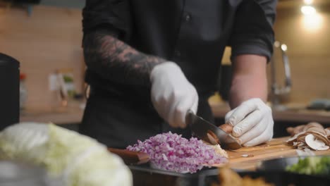 Mushroom-being-sliced-on-a-wooden-board-by-professional-chef-in-an-elegant-black-shirt-with-tattoos-and-white-gloves