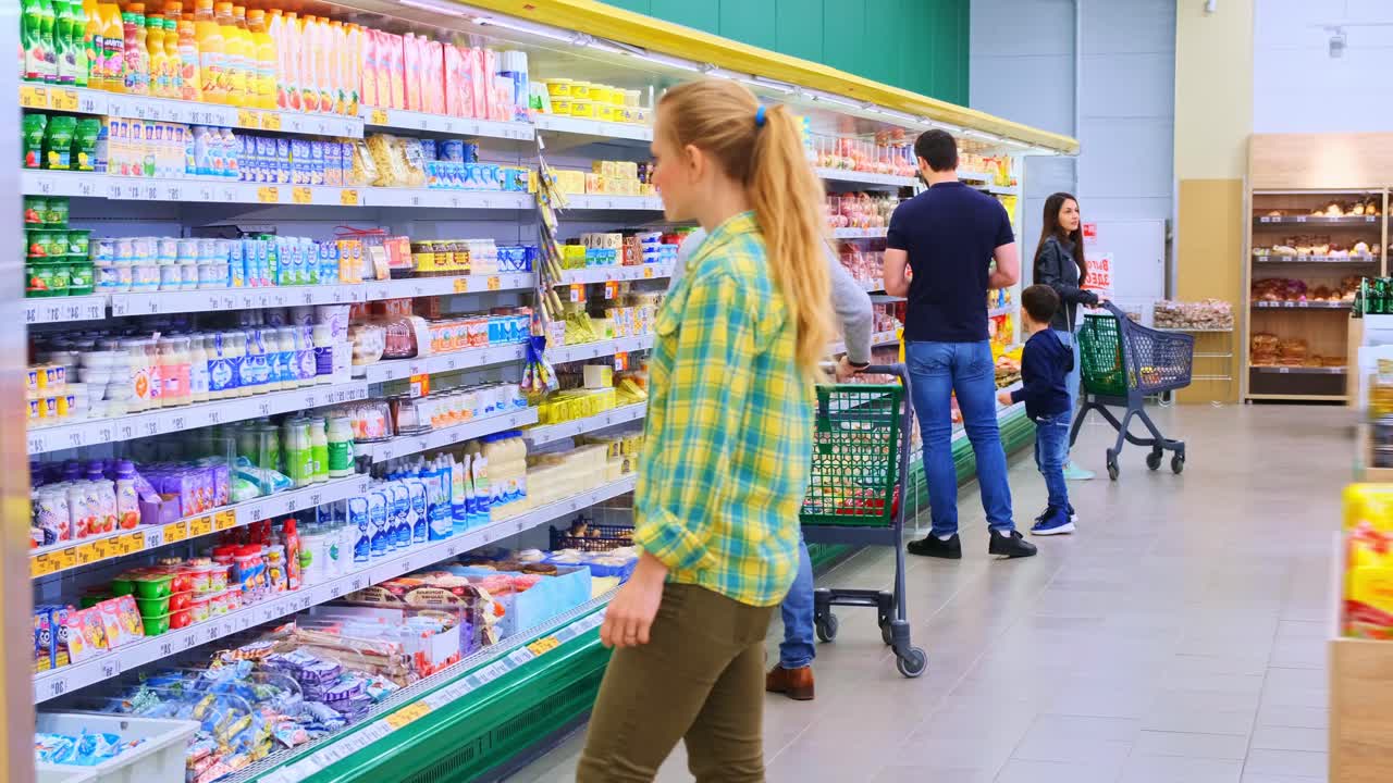 A Busy Supermarket Scene Captured in Two Frames: Shoppers Browsing Shelves for Groceries and Snacks in a Brightly Lit Aisle with Varied Products and Cart Access