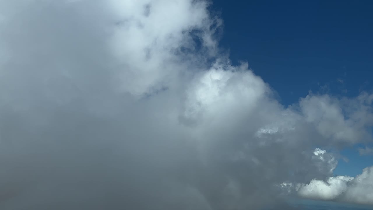 A pilot&rsquo;s perspective: flying across some fluffy cumulus clouds in a sunny summer afternoon