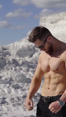 healthy man with athletic body outdoors. portrait of a handsome sportsman on white hill background in a sunny summer day. sporty lifestyle. vertical video